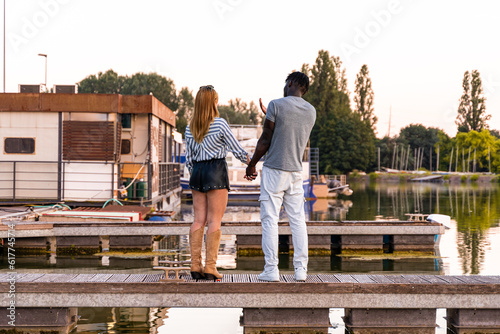 young multiracial loving couple holding hands on a quay of a river port © Marino Bocelli