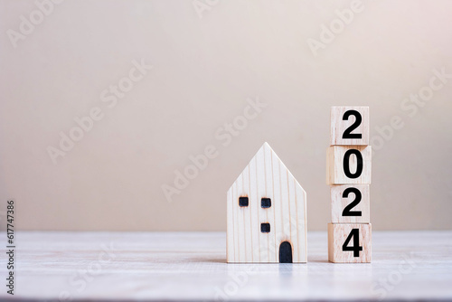 2024 Happy New Year with house model on table wooden background. Banking, real estate, investment, financial, savings and New Year Resolution concepts