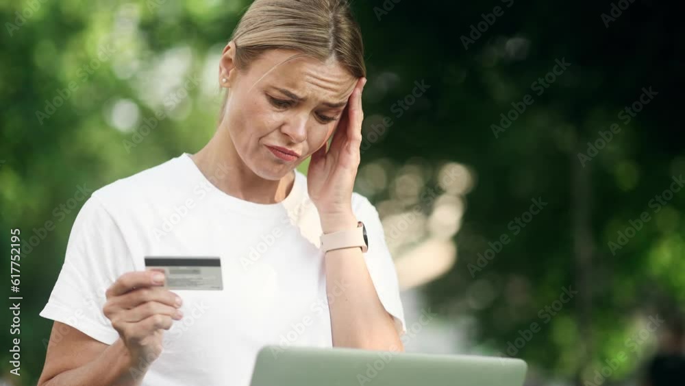 Confused blond woman with credit card thoughtfully pondering on screen while has problem with online order payment error or blocked bank account doing shopping at internet on laptop at park Confused blond woman with credit card thoughtfully pondering on screen while has problem with online order payment error or blocked bank account doing shopping at internet on laptop at park