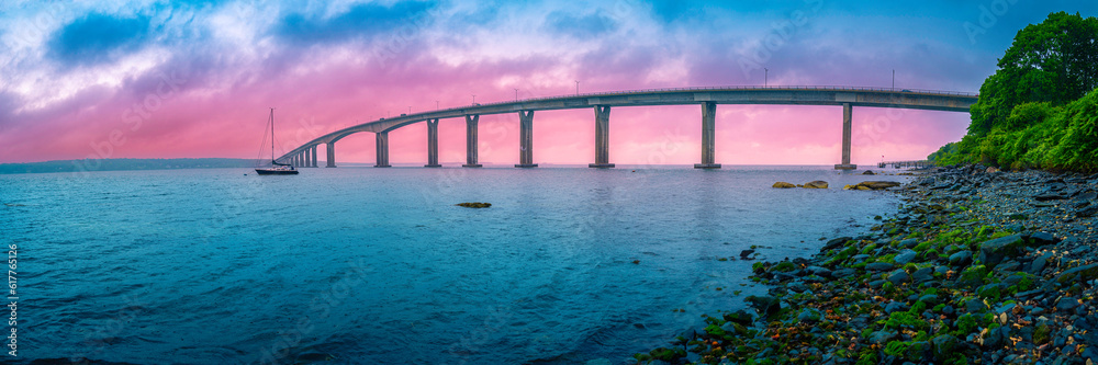 Dramatic beautiful stormy sunset panorama over Jamestown Verrazzano Bridge and Narragansett Bay in North Kingstown, Rhode Island, with a moored yacht in the rain.