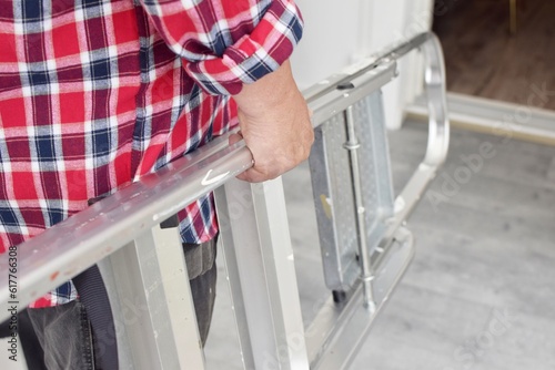 A man in work uniform holds a ladder. Repair concept.