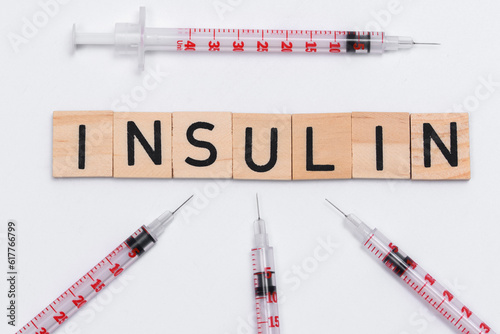 Napis insulina ułożony na białym tle, obok strzykawek insulinówek