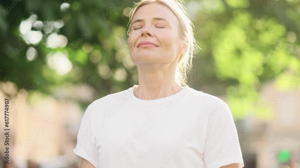 Portrait of confident mature blond woman looking ahead and exhaling fresh air taking deep breath and reducing stress after work at park Successful businesswoman resting for peaceful mind outdoors Portrait of confident mature blond woman looking ahead and exhaling fresh air taking deep breath and reducing stress after work at park Successful businesswoman resting for peaceful mind outdoors