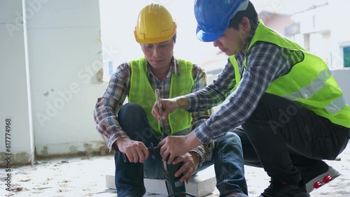 Engineer teaching worker for use electric jackhammer for perforator equipment making holes the floor to be strong at construction site, Concept of worker and residential building
