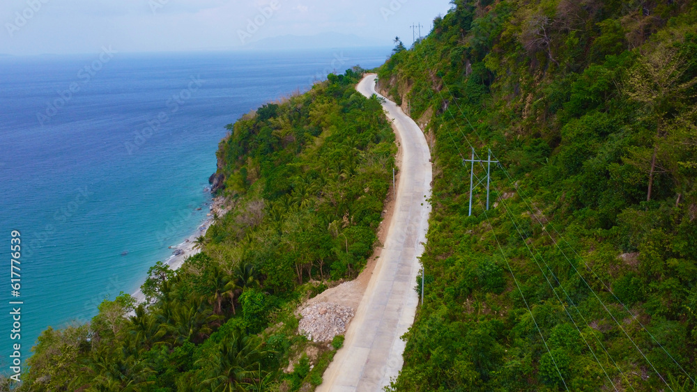 Path to the sea. Road along the sea. A concrete road runs along the sea coast of a tropical island in the jungle.