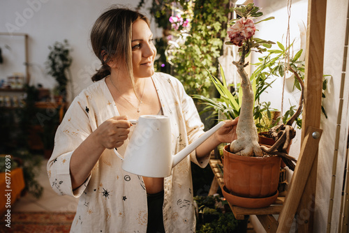 woman watering flowering adenium plant