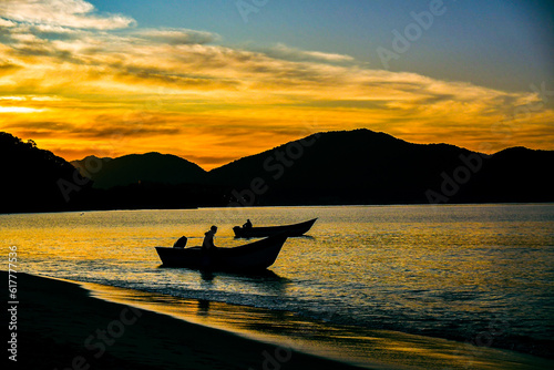 Silhueta de dois barcos ao nascer do sol no mar no litoral do Brasil, na praia da Cocanha em Caraguatatuba.