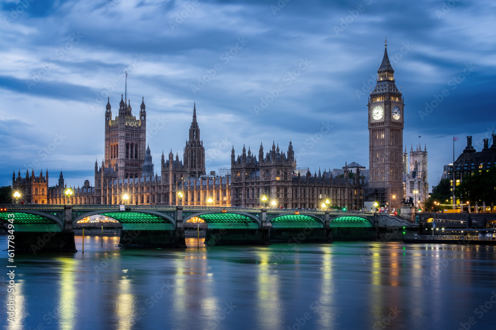 View of Westminster palace and bridge over river Thames with Big Ben illuminated at night in London, UK