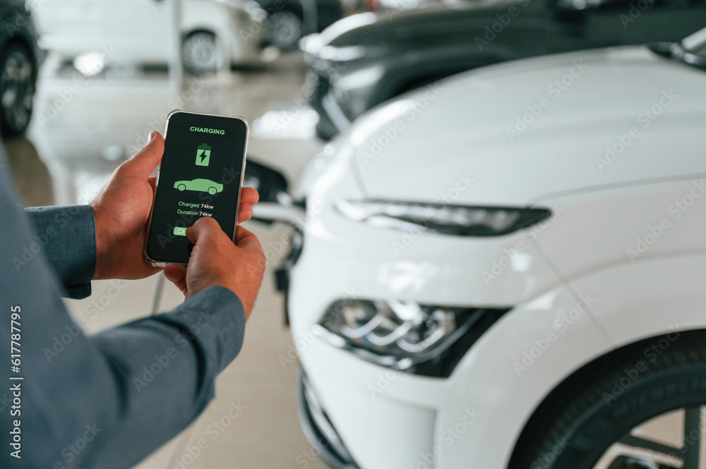 Information of charging process. Close up view of man that is with electrical car Information of charging process. Close up view of man that is with electrical car