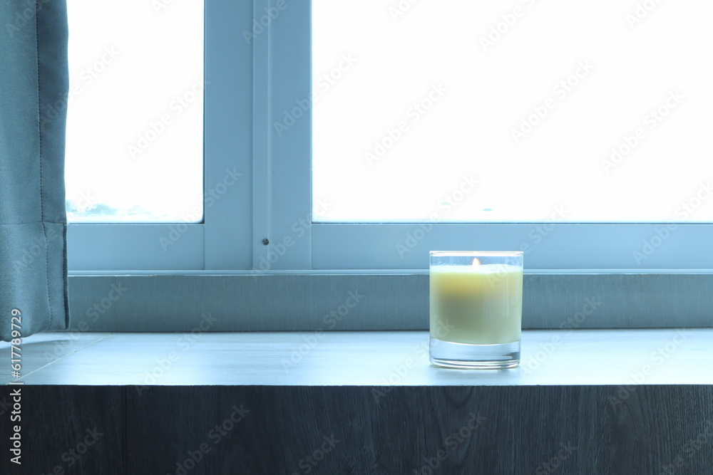 the burning luxury aromatic scented candle glass decorated on the wooden table to make better ambient scent on valentine day with background of sunlight from the window in morning the burning luxury aromatic scented candle glass decorated on the wooden table to make better ambient scent on valentine day with background of sunlight from the window in morning