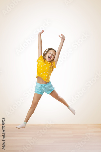  portrait of a little girl jumping while on a white background in a studio. happy joyful kid girl in comfortable trendy wear jumping high..