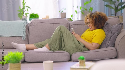 Relax, texting and woman with phone on a sofa for social media, reading and chatting in her home. Smartphone, app and female person in a living room chilling on day off and online dating website photo