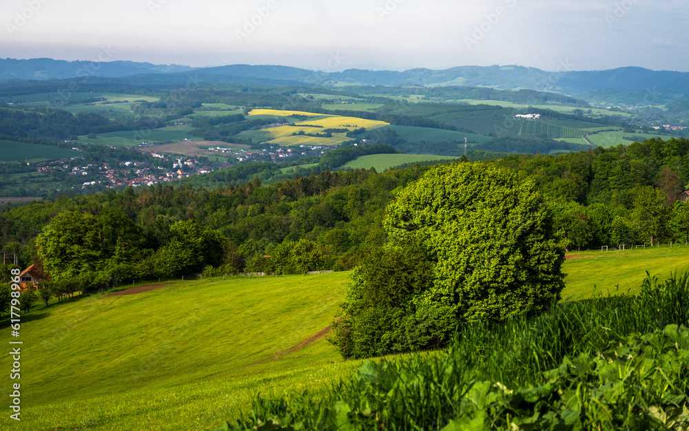 Meadow, field, forest, house and village with hills on background near Lipa.