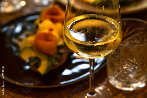 Glass of wine and plate with food on restaurant table.