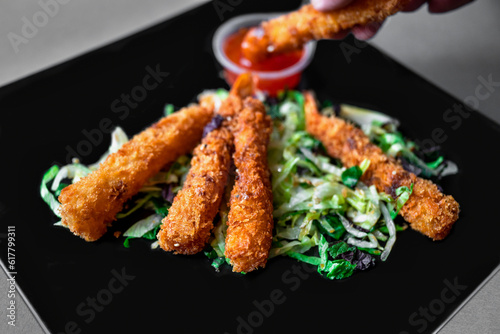 Hand dips breaded fried shrimp into spicy sauce