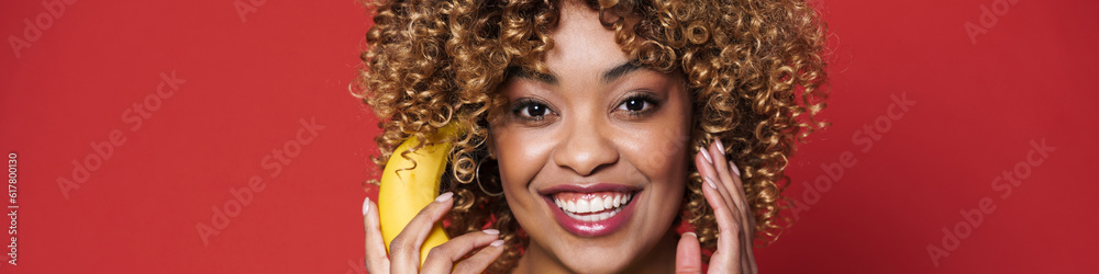 Young black woman laughing while posing with banana Young black woman laughing while posing with banana