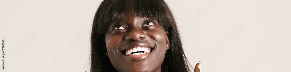 Fototapeta premium Young beautiful smiling african woman with bob haircut pointing up
