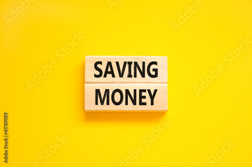 Saving money symbol. Concept words Saving money on wooden blocks on a beautiful yellow table yellow background. Business, support and saving money concept. Copy space.