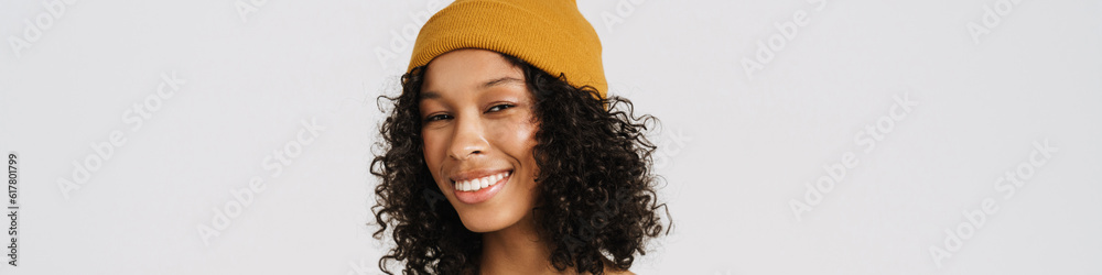Fotografie Black woman wearing hat smiling while using mobile phone