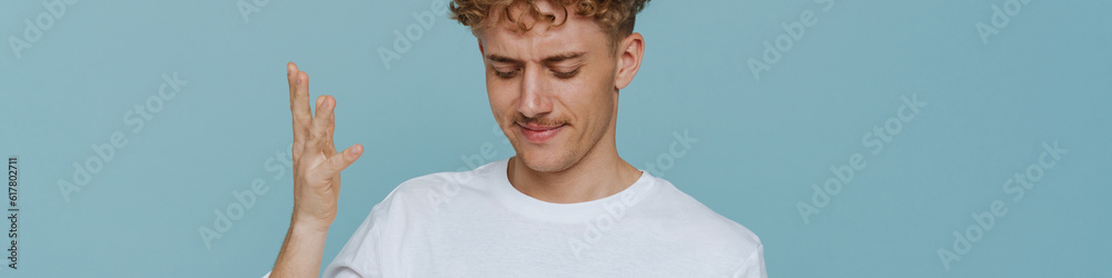 Obraz premium Young handsome curly thoughtful man with mustache with raised hand