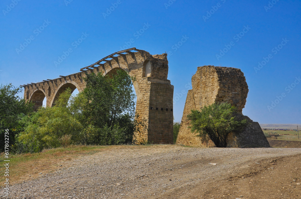 Stone old ruined railway bridge against the blue sky