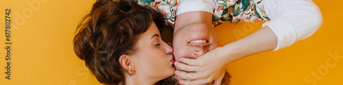 Young beautiful short-haired woman kissing her smiling curly boyfriend