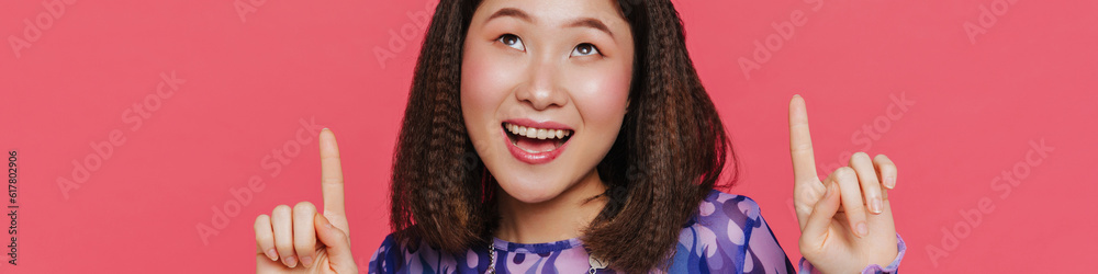 Young cute happy asian girl looking and pointing upward Young cute happy asian girl looking and pointing upward