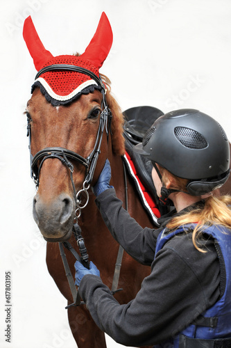 Girl in a jockey outfit with a beautiful brown horse isolated on white background