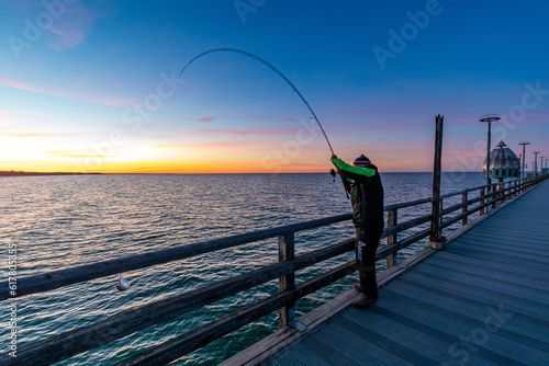 Fototapeta Naklejka Na Ścianę i Meble -  Anglerglück bei Sonnenuntergang auf der Seebrücke in Zingst an der Ostsee.