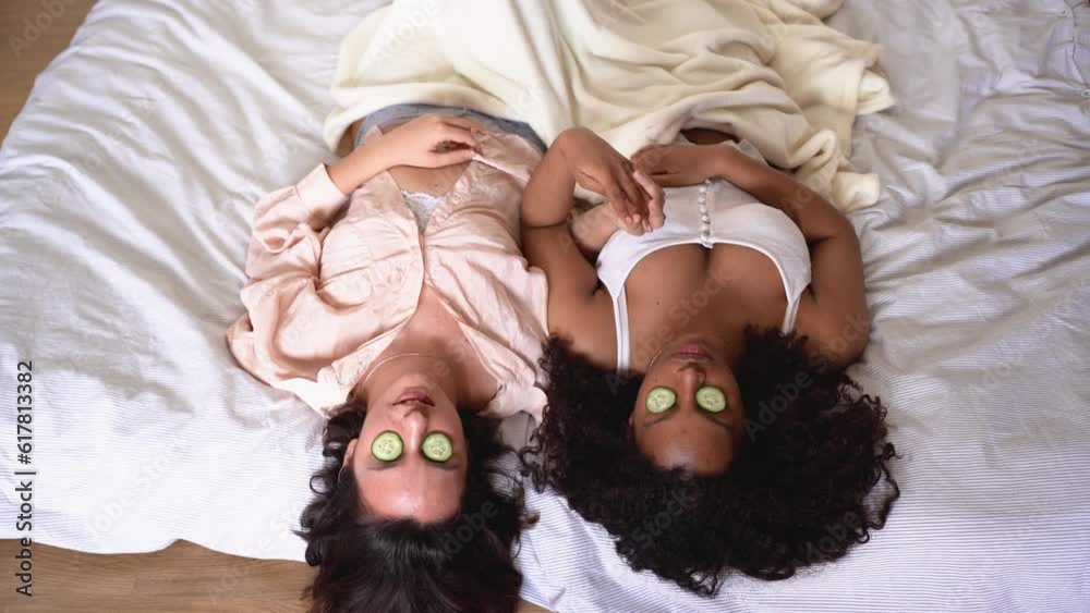 From above of diverse women lying on blanket with cucumber slices on eyes From above of diverse women lying on blanket with cucumber slices on eyes