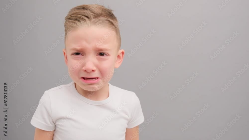 A little boy looks into the camera and cries. Portrait of a child on a pink background. A little boy looks into the camera and cries. Portrait of a child on a pink background.
