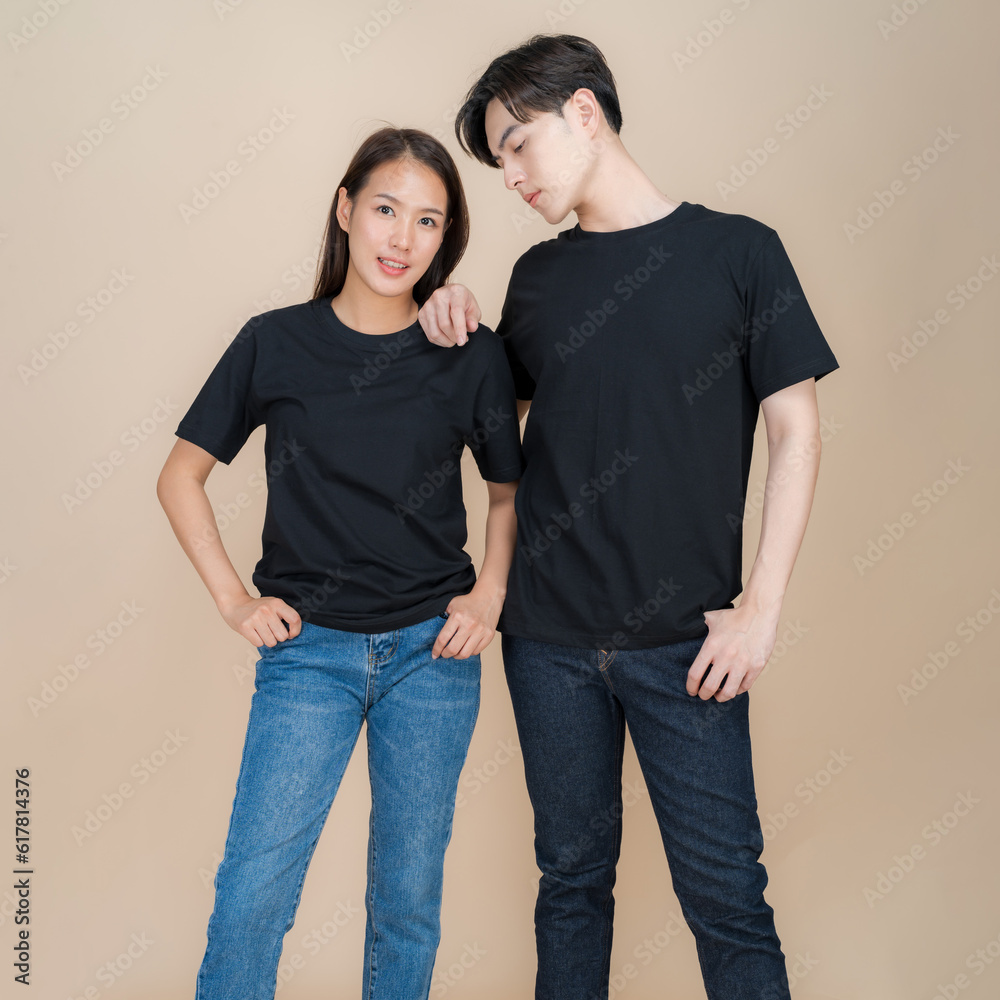 An image of a male and female fashion model standing in black t-shirt and jeans standing in studio on beige background An image of a male and female fashion model standing in black t-shirt and jeans standing in studio on beige background