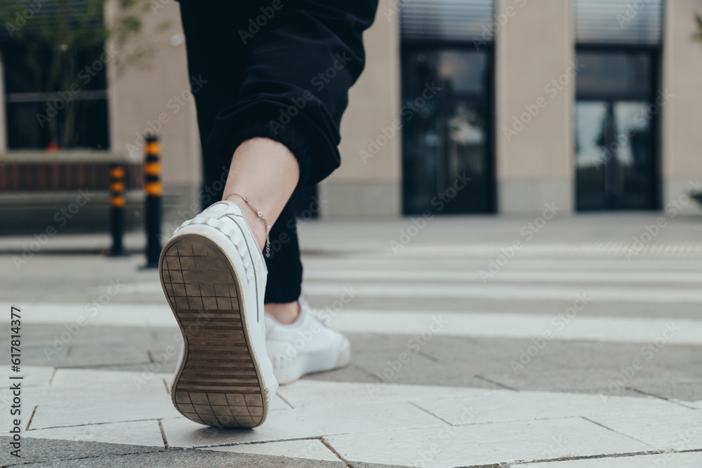 Legs of a girl in White Leather Sneakers Crosses the Street on a Pedestrian Crossing Legs of a girl in White Leather Sneakers Crosses the Street on a Pedestrian Crossing