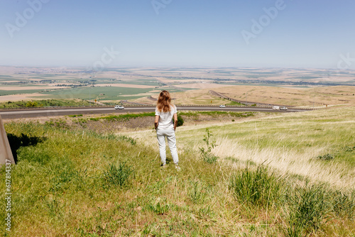 Beautiful summer landscape with meadows and a road from a bird's eye view. Nature in Oregon. A girl in sportswear with red hair walks in a summer meadow, rests in nature, admires nature