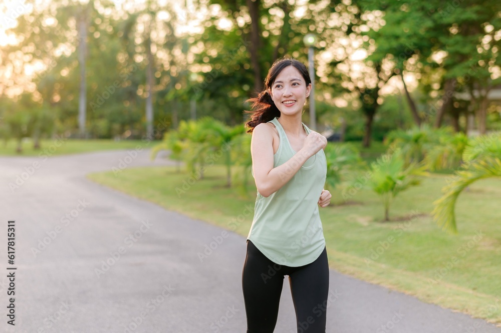 Fit Asian young woman jogging in park smiling happy running and enjoying a healthy outdoor lifestyle. Female jogger. Fitness runner girl in public park. healthy lifestyle and wellness being concept Fit Asian young woman jogging in park smiling happy running and enjoying a healthy outdoor lifestyle. Female jogger. Fitness runner girl in public park. healthy lifestyle and wellness being concept
