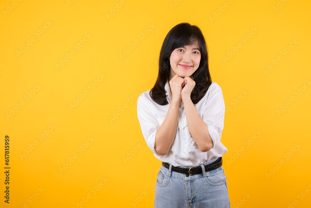 Young asian woman wearing white shirt and denim jean plants feeling happy smile expresses happiness feels joyful isolated on yellow background. Positive feeling gesture concept. Young asian woman wearing white shirt and denim jean plants feeling happy smile expresses happiness feels joyful isolated on yellow background. Positive feeling gesture concept.