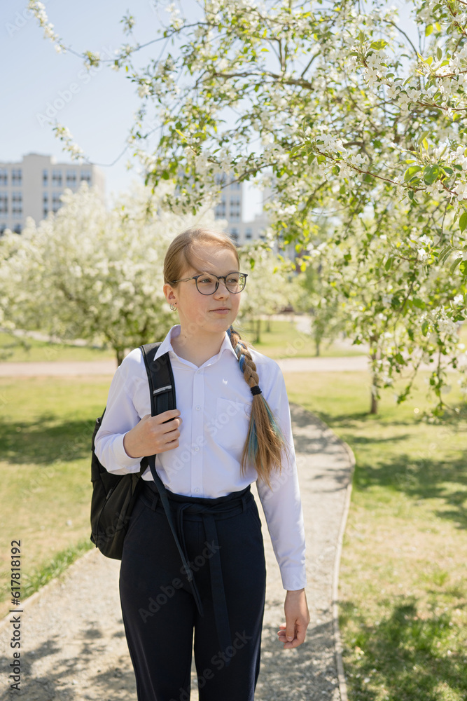 Positive teenage girl standing with school bag in park Positive teenage girl standing with school bag in park