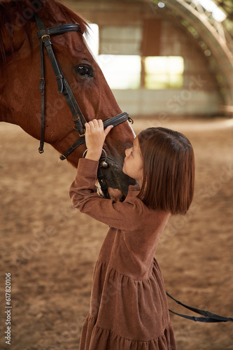 Cute little girl is with horse indoors © standret