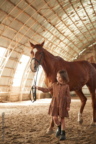 Walking together. Cute little girl is with horse indoors © standret