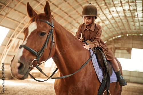 Riding the animal. Cute little girl is with horse indoors © standret