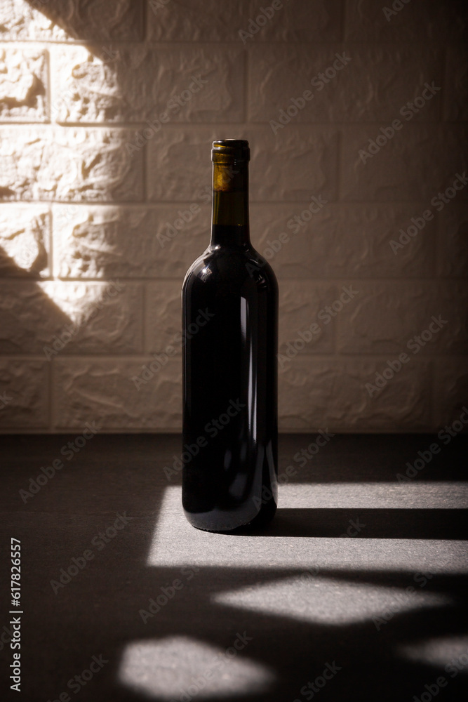 Unlabeled red wine bottle mockup on gray stone surface, textured white