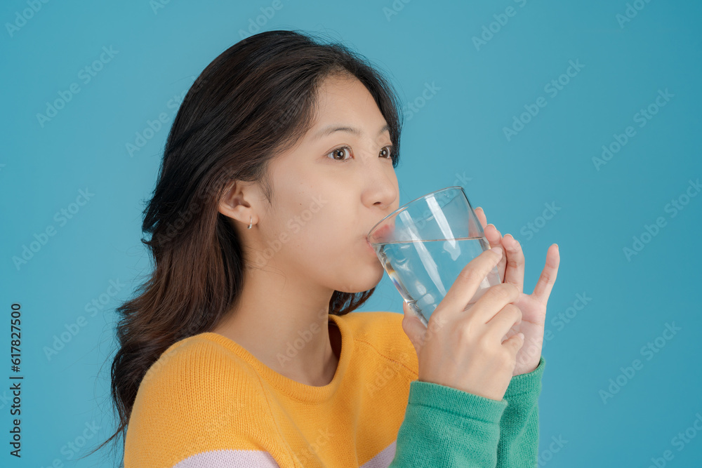 Beautiful young woman smiling happily while holding a drinking glass in her hand Beautiful young woman smiling happily while holding a drinking glass in her hand