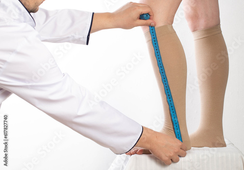Doctor phlebologist - a vascular surgeon selects the size of the compression stockings of the patient's girl. Measure your feet with a measuring tape. Varicose veins in the legs. photo