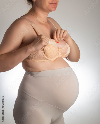 A pregnant woman puts special anatomical inserts into her bra against the flow of milk. Nursing mother and protection against leakage of milk from the breast. photo