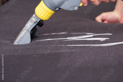 Cleaning the sofa with a special washing vacuum cleaner from dirt. Dry cleaning of sofas and upholstered furniture, close-up. Copy space for text