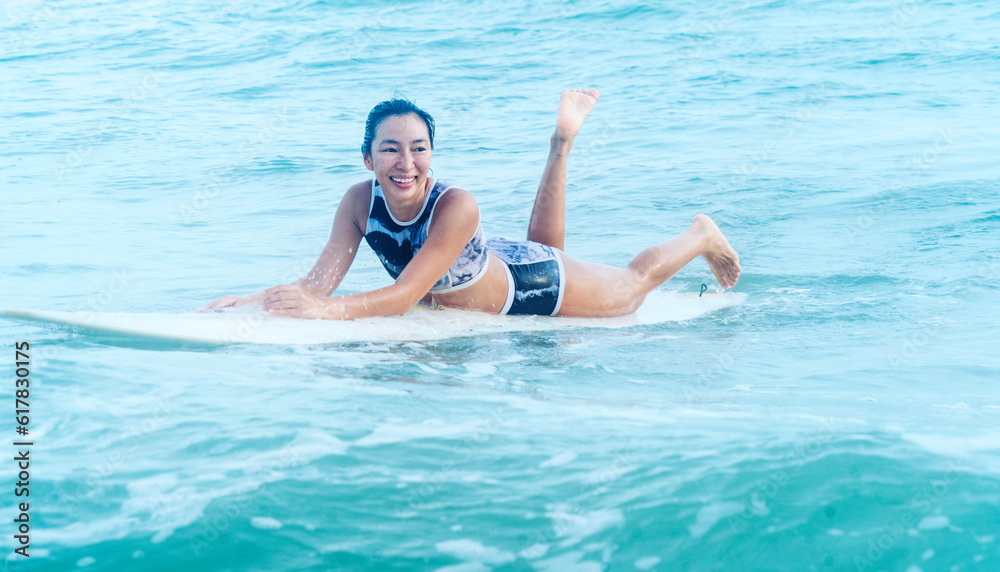 Asian women wearing swimsuits hobby happy fun lying surfing waves on board in the sea is an exciting water sport on the beach in United International Pictures Thailand, fitness, healthy, exercise, act