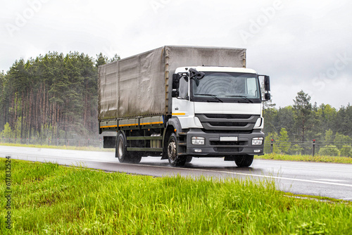 A tilt truck transports cargo on a highway in rainy weather on a slippery road. The concept of import substitution. Copy space for text photo