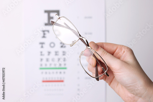 vision correction glasses in hand against the background of a vision test table with space for text