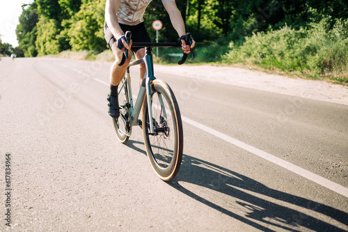 Close-up shot of male cyclist riding a professional road bike on the road outside the city. © bodnarphoto
