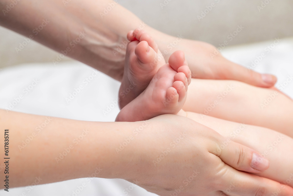 Mother massages baby on legs. Newborn skin care, close-up